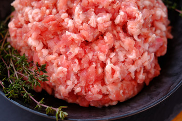 forcemeat with sprigs of thyme in a black cup on a black  background.Meat food. Ground chopped meat...