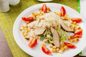 Caesar salad with chicken and vegetables in a plate on the table
