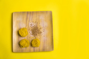 Diet and weight loss theme on the yellow background. Buckwheat and macaroni products in the wooden plates. Slow carbohydrates on the orange background with copy space. italian and russian cuisine