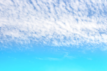 soft white clouds streak in colorful blue sky