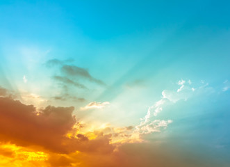 orange and yellow sunset light on bright blue sky with sun rays