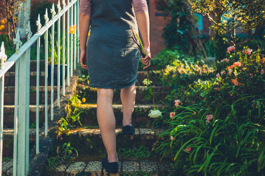 Woman walking up steps outside house in front garden