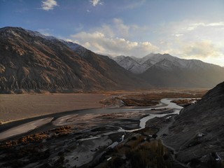Fototapeta na wymiar Mountain road. White peaks. Dangerous cliffs. Pamir. Fast river. Rocks. Dangerous road. Roof of the world. Talikistan. Badakhshan.Traveling in the mountains. Afganistan.