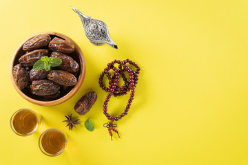 Fototapeta na wymiar Table top view image of decoration Ramadan Kareem, dates fruit, aladdin lamp and rosary beads on yellow background. Flat lay with copy space.