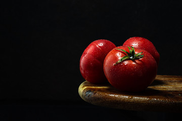 Fresh ripe red tomatoes on wooden table.Close up,dark mood food styling.