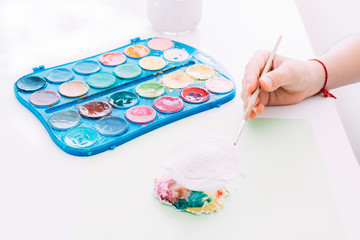 Child hands painting white clay figure with colored watercolors. Painting, education and relaxation concept.
