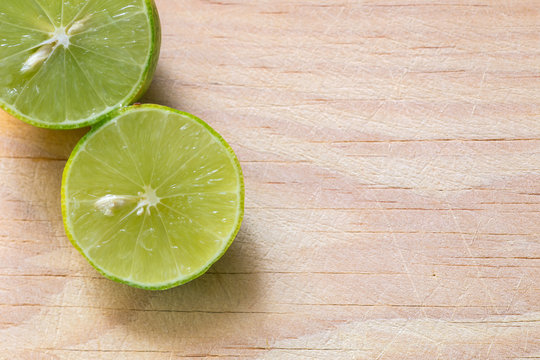 Un lim&oacute;n verde y jugoso cortado en una tabla de madera iluminada con luz natural