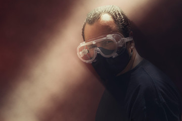 White man in red background, wearing glasses and protective mask, in serious attitude, angry, thoughtful, about to attack, watching his victim to hunt her down