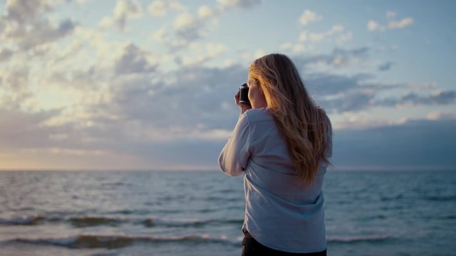 Blonde Woman Photographer Taking Photos of the Ocean.