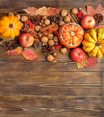 autumn composition with pumpkins, cones, berries, apples, nuts, cinnamon on wooden table background. copy space