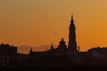sunset in Zaragoza with the cathedral in the background and a plane taking off