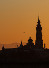 Naklejka premium sunset in Zaragoza with the cathedral in the background and a plane taking off