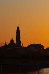 Fototapeta na wymiar sunset in Zaragoza with the cathedral in the background and a plane taking off