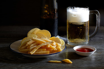 Beer and snack in white dish put on gray wooden table and dark background