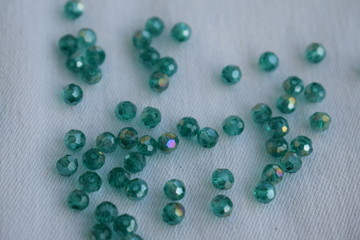 Green faceted glass beads on a white background.