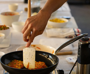 Hand of woman cooking a vegetable food on a pan