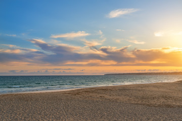 Landscape of beautiful sunset on the ocean, with sand, horizon with a blue sky. Portugal.