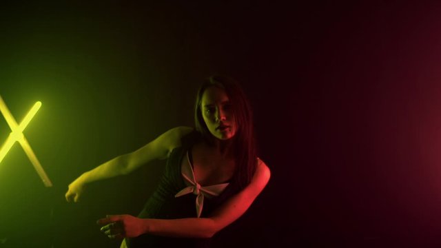 Beautiful young brunette girl in a nude outfit dancing in a studio with multi-colored light, background, slow motion