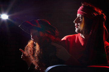 Woman in red sweater and the turban of wizard or sorcerer with boy on black background. Actress...