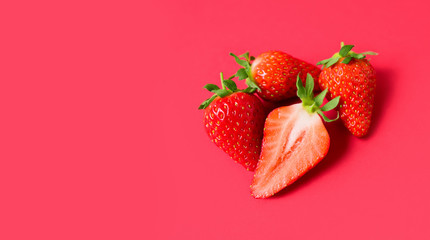 Ripe juicy orgaic strawberries on a red background.