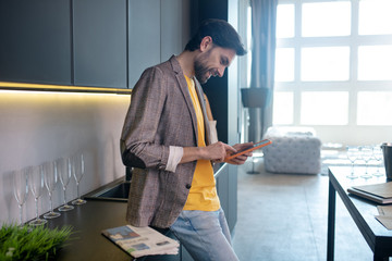 Young bearded man holding a tablet in his hands and reading something on internet