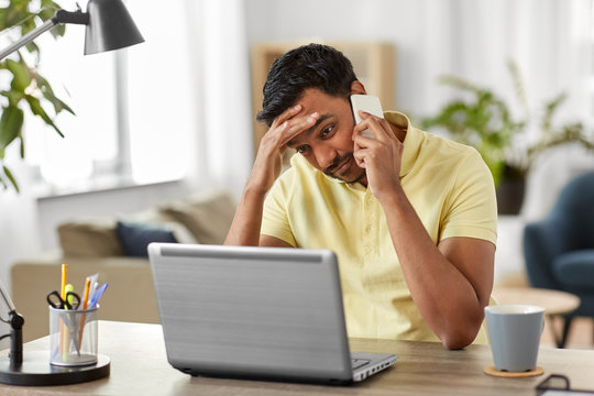 technology, remote job and business concept - stressed indian man with laptop computer calling on smartphone at home office