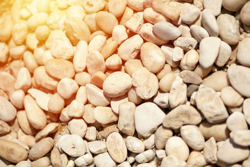 Round pebble stones on beach sand. Top view.