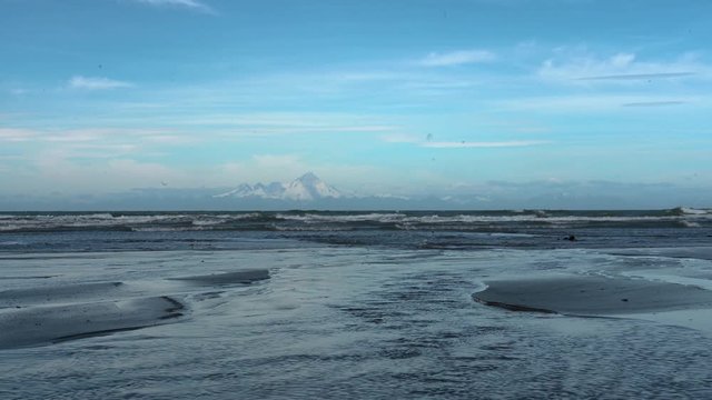 The rough sea of Alaska in the foreground and the mountains of the Katmai Penisula in the back. The mountains are vulcanos and covered in ice.