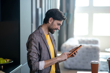 Fototapeta premium Dark-haired bearded man with a tablet in his hands.