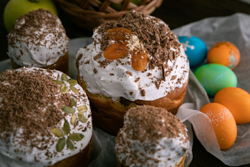 Easter cakes, eggs and apples in the basket. On the brown table.