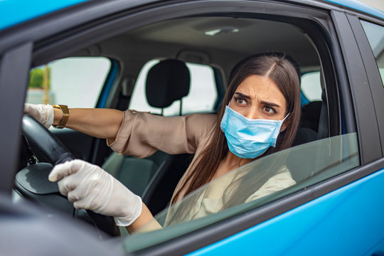 Infection prevention and control of epidemic. World pandemic. Stay safe. Young woman wearing protective face mask while driving car. Protection against the novel coronavirus infection.