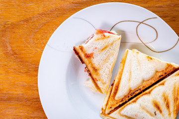 top view bitten sandwiches are placed in a dish that has messed up the bread crumbs on wooden table