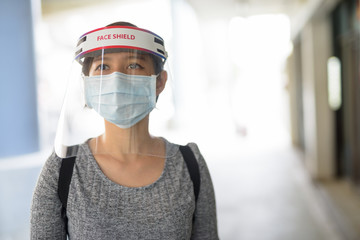 Fototapeta na wymiar Young Asian woman wearing mask and face shield for protection from corona virus outbreak in the city outdoors