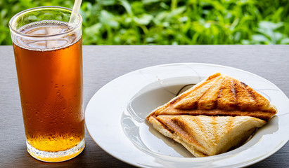 two toast sandwiches with strawberry jam and a glass of ice tea lemon