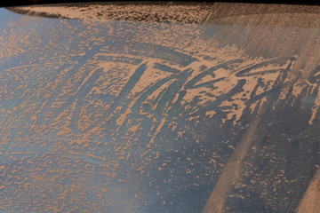 Rear window of a car covered with sand. Dutch sense means: that the car could perhaps be washed