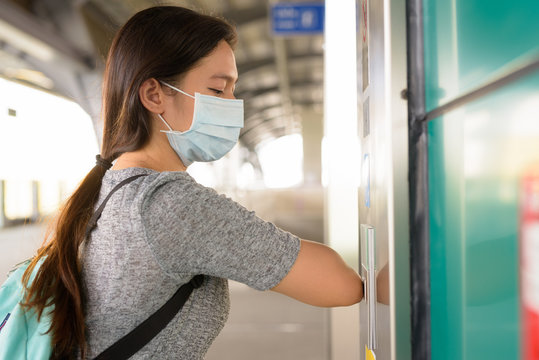 Young Asian woman with mask pressing elevator button with elbow to prevent spreading the corona virus at skytrain station