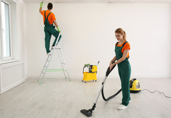 Professional young janitor vacuuming indoors. Cleaning service