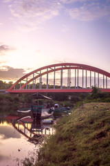 Sunrise at Samota Bridge in Sumbawa City, Indonesia. There is a traditional wooden boat too under the bridge