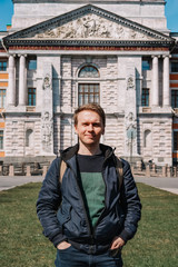 Portrait of a young man in a jacket and with a backpack on the background of an architectural monument, a historical castle in Saint Petersburg