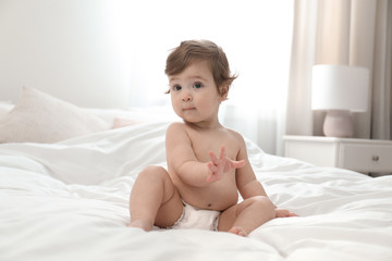 Cute little baby in diaper on bed