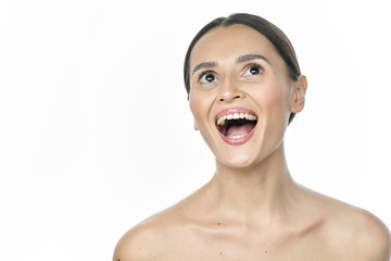 A girl with clear skin screams and looks at the camera on a white background