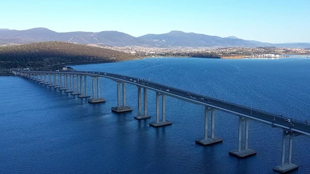 Hyperlapse orbiting around the Tasman bridge over the flowing Derwent river in Tasmania Australia, with traffic, cars and trucks, crossing in morning light.