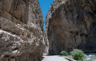 mountains of Central Asia. a narrow road between mountains. rapid river and sparse vegetation. there are no people.
