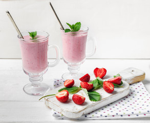 Glass of fresh strawberry and yogurt smoothie on white wooden table