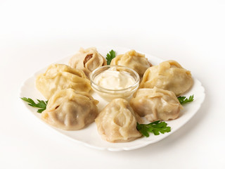 Side view of a traditional Asian dish - manti on a plate with sour cream