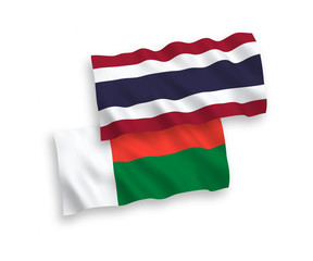 National vector fabric wave flags of Madagascar and Thailand isolated on white background. 1 to 2 proportion.