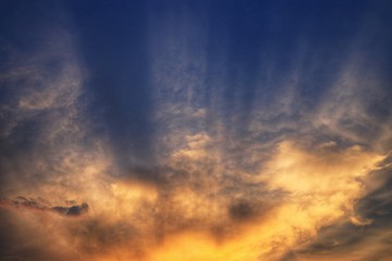 bursting sky. light ray shining through the clouds. cloud caught by last light of the day and grow warm orange yellow in a dramatic fashion. hope God inspiration and silver linings concepts.