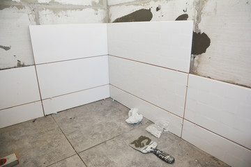 A close up on bathroom renovation with newly laid slip resistant square gray floor tiles and...