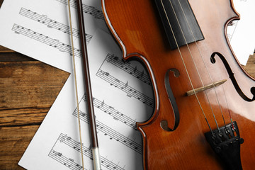 Beautiful violin, bow and note sheets on wooden table, flat lay