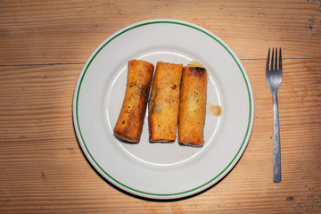 three croquettes on a plate on a wooden table